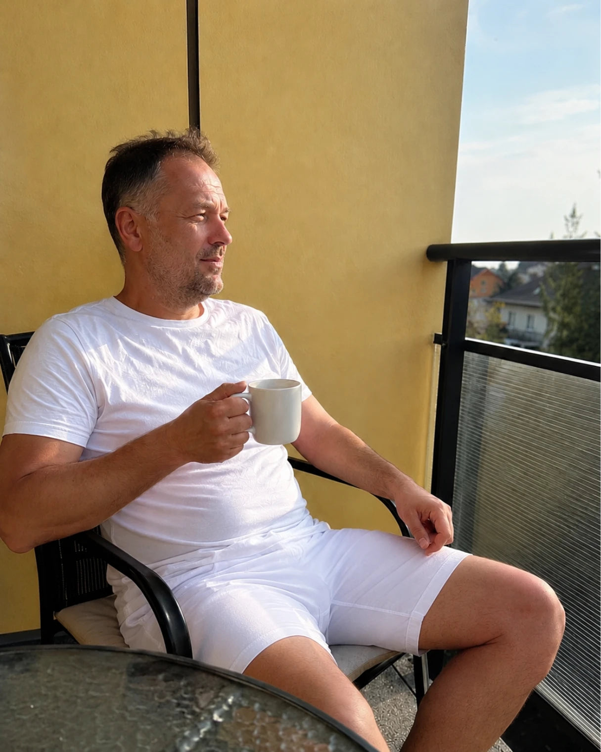 Kunde trägt weiße Cotton Majesty Boxershorts entspannt auf dem Balkon